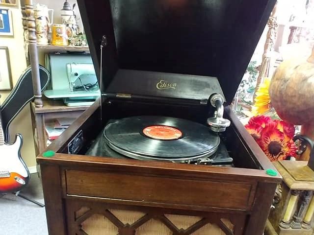 Antique record player with “Edison” stylus and vinyl record on display indoors.