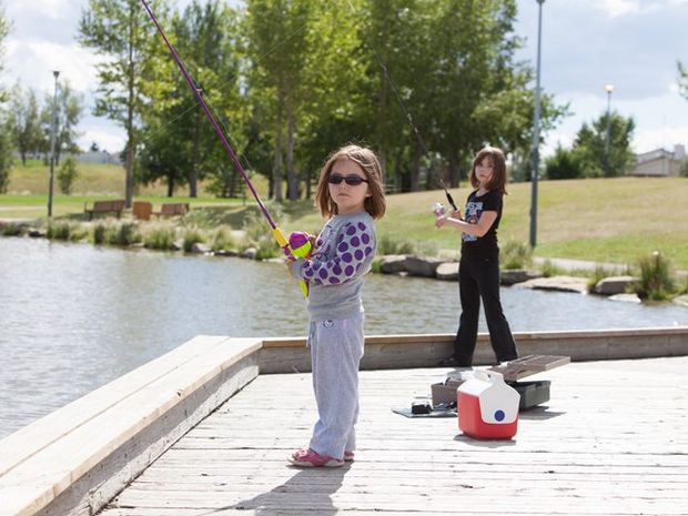 Two young girls fishing off the dock in Nose Creek Provincial Park.