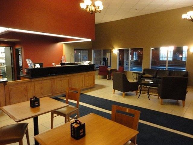 Hotel lobby with reception desk, tables, chairs, and windows in Best Western Olds.