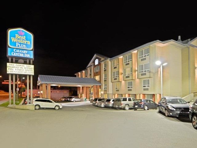 Best Western hotel exterior at night with bright lights and parked cars.