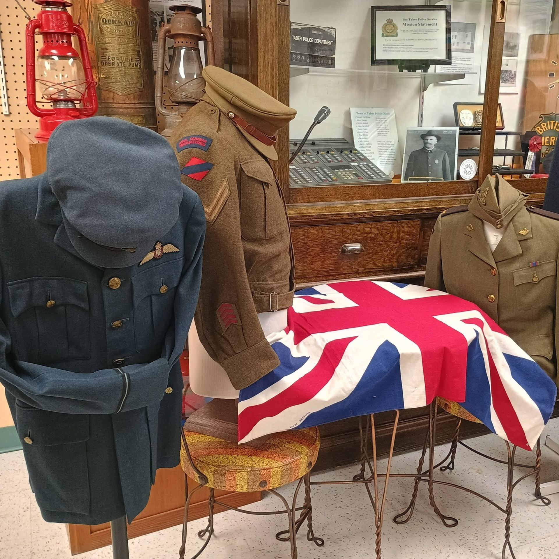 Three military uniforms displayed with a Union Jack flag and lanterns