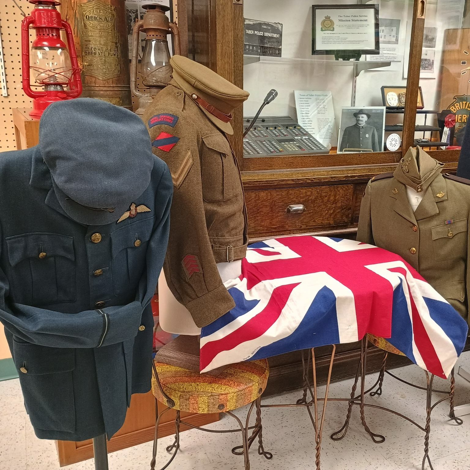 Three military uniforms displayed with a Union Jack flag and lanterns