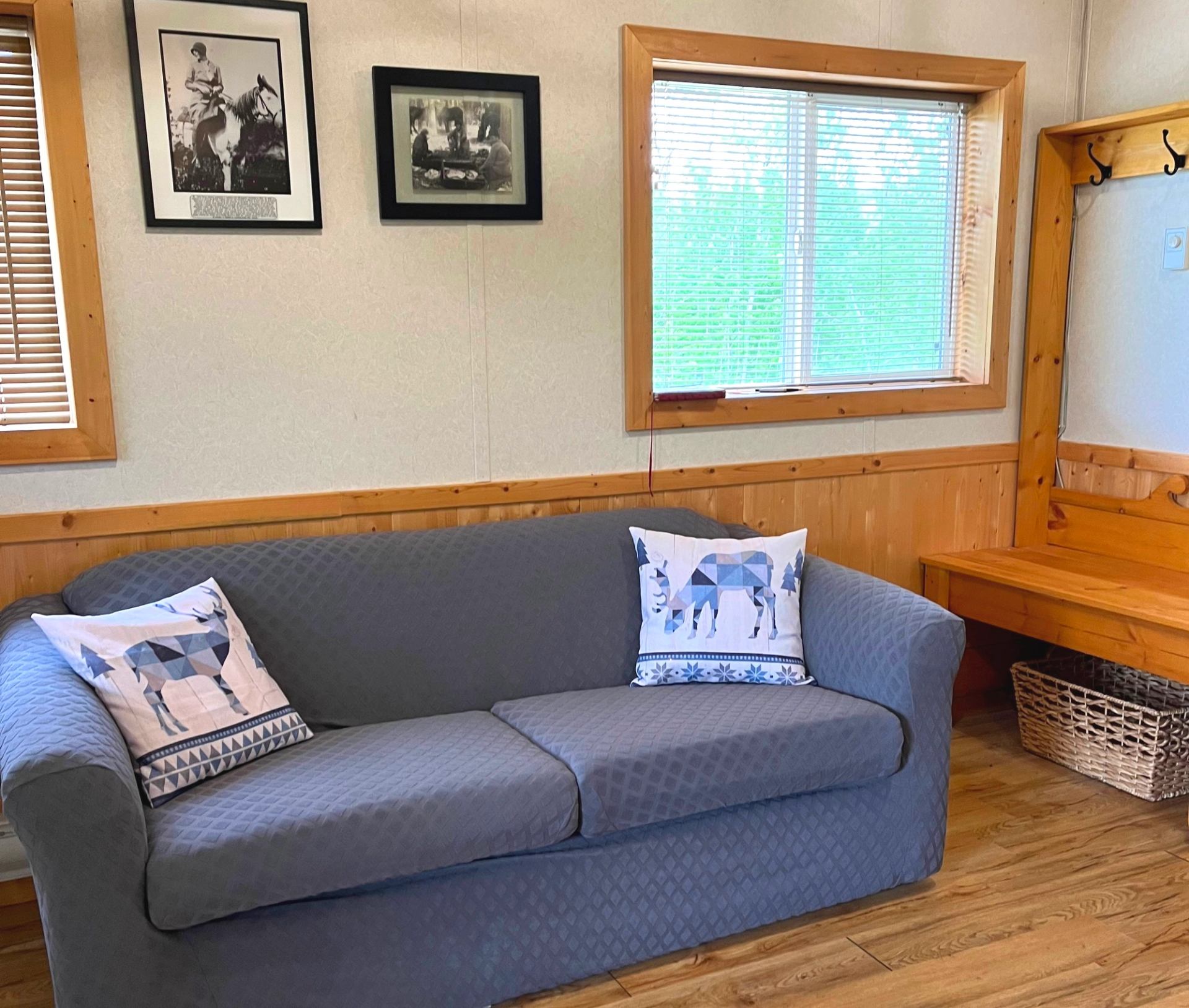 Cozy living space with gray sofa, wooden trim, framed photos, and a window view