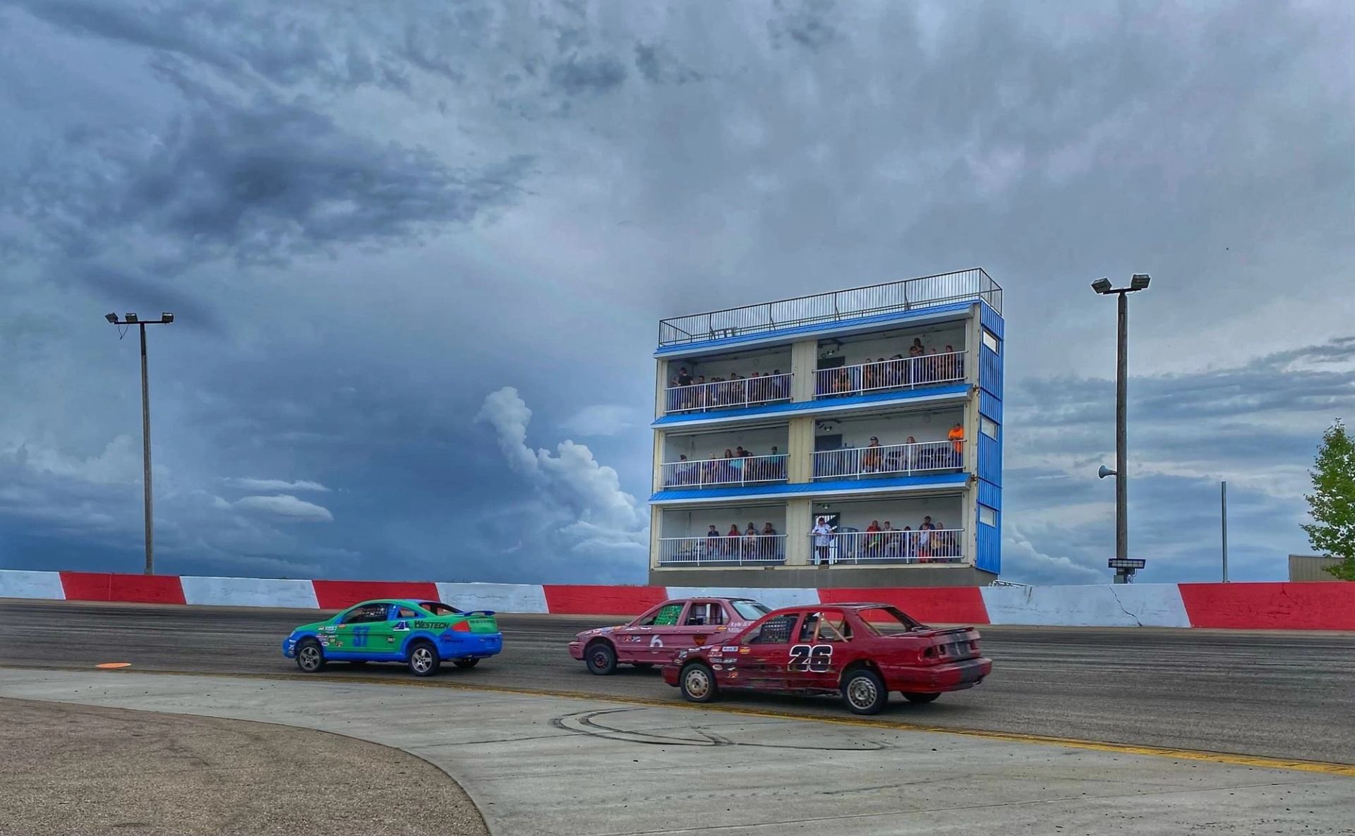 Race cars drive past a multi-level viewing tower during Saturday NASCAR racing.