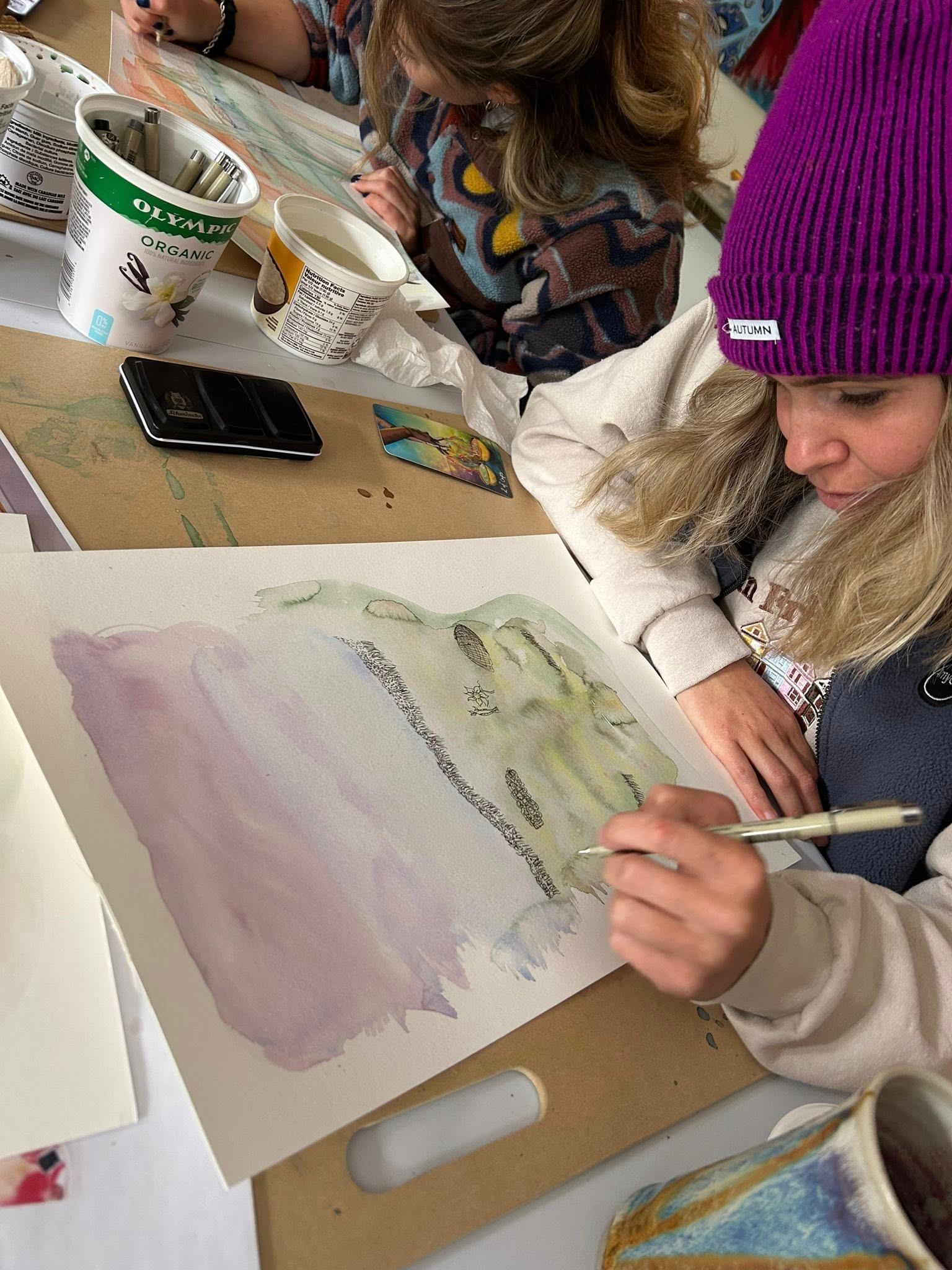 Two people painting with pastel colors at a table.