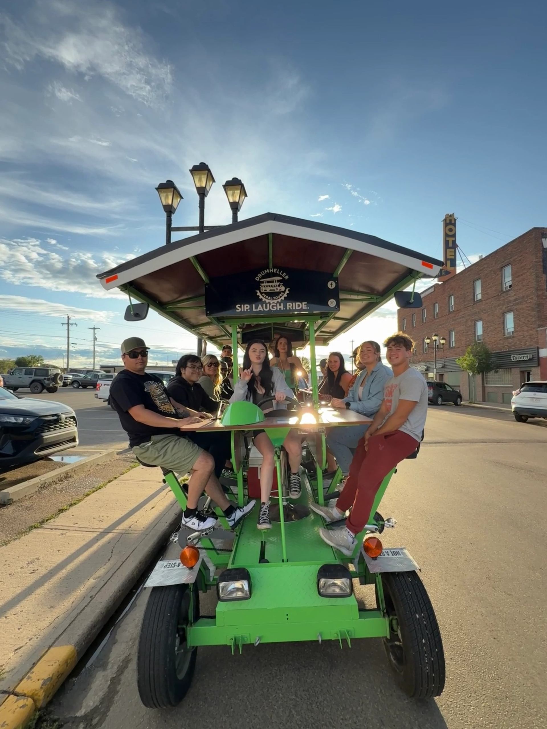 A group of people riding on a green pedal-powered party trolley.