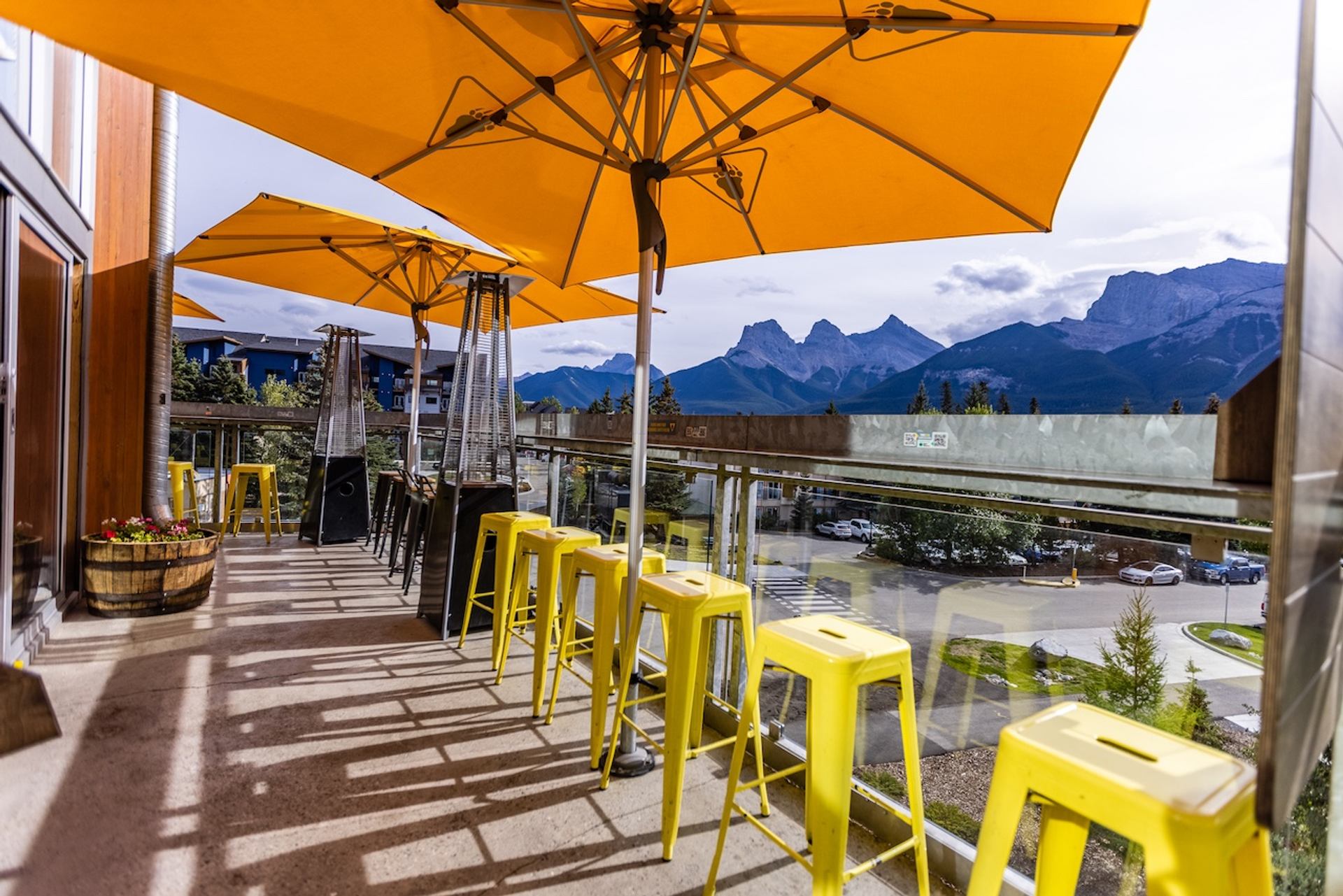 Outdoor patio with yellow umbrellas, stools, and mountain views.