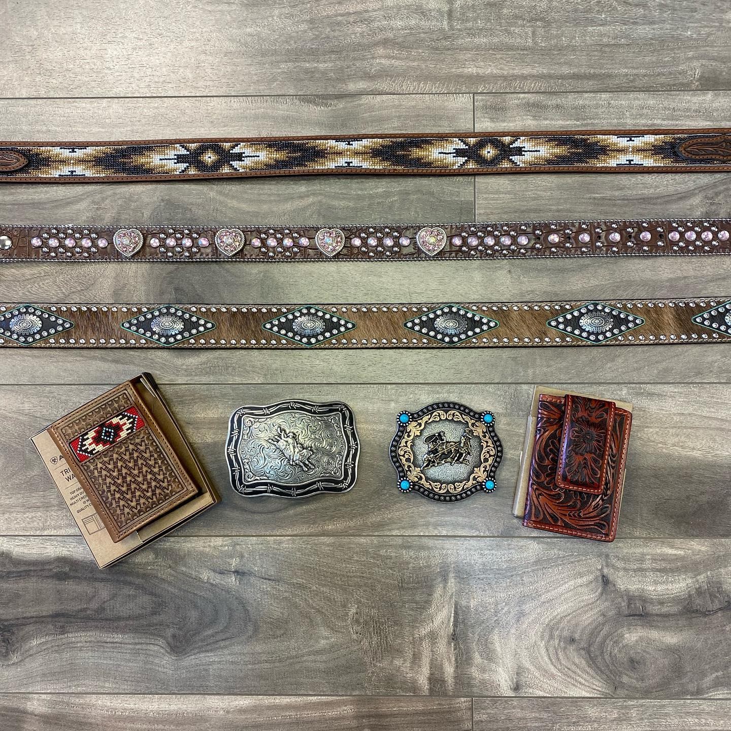 Studded western belts and wallets displayed on a grey wooden counter at Silverado Country Western We.