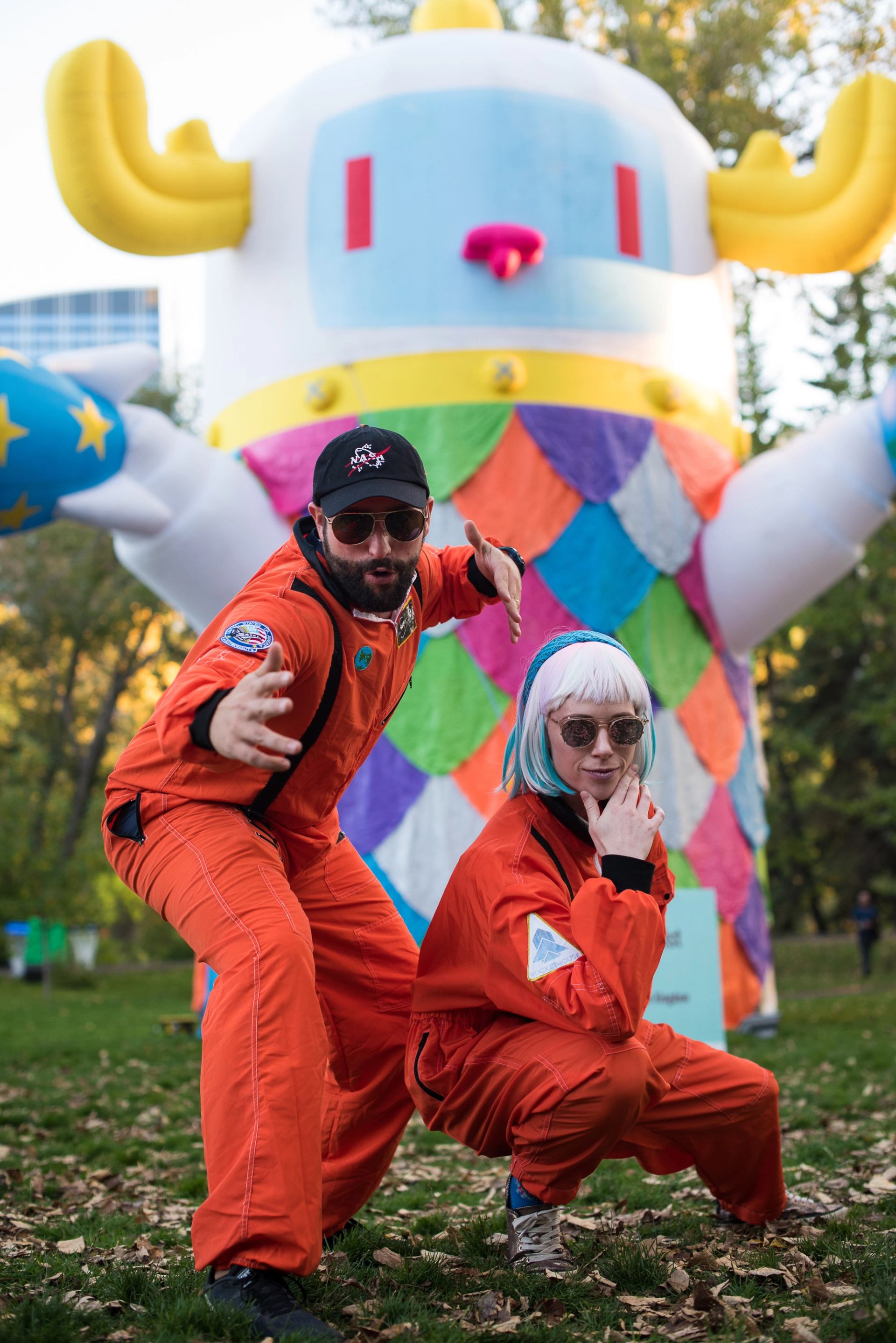 A man and woman dressed as astronauts pose in front of an inflatable robot.