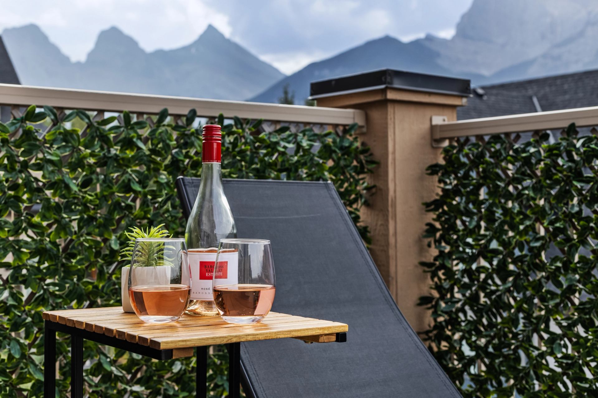 Rosé bottle and two glasses on a patio table overlooking mountains.