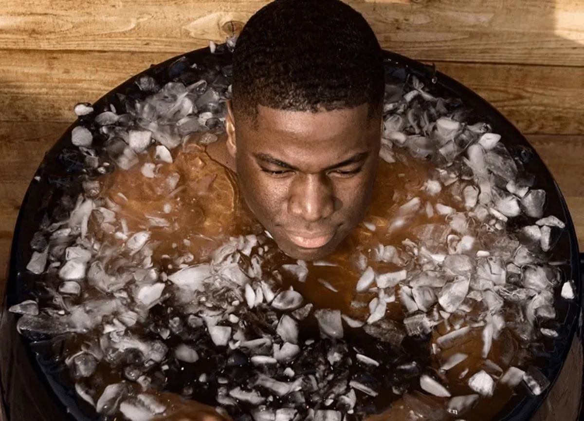 Person sitting in a round tub filled with ice cubes and cold water.