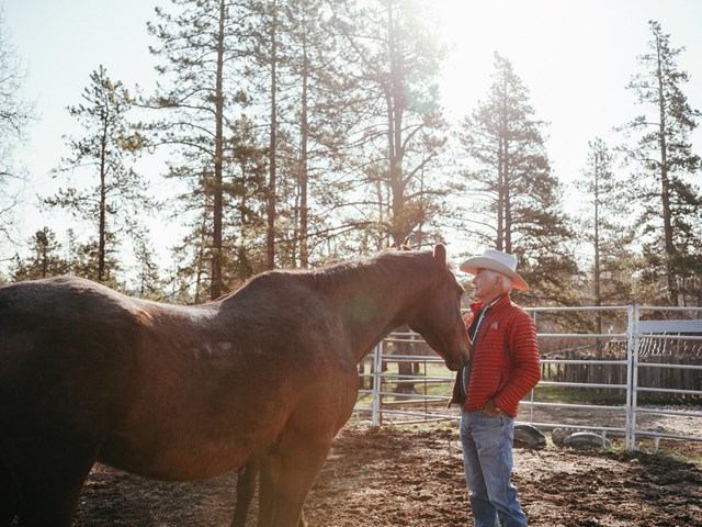 Man standing in front of a horse petting it.
