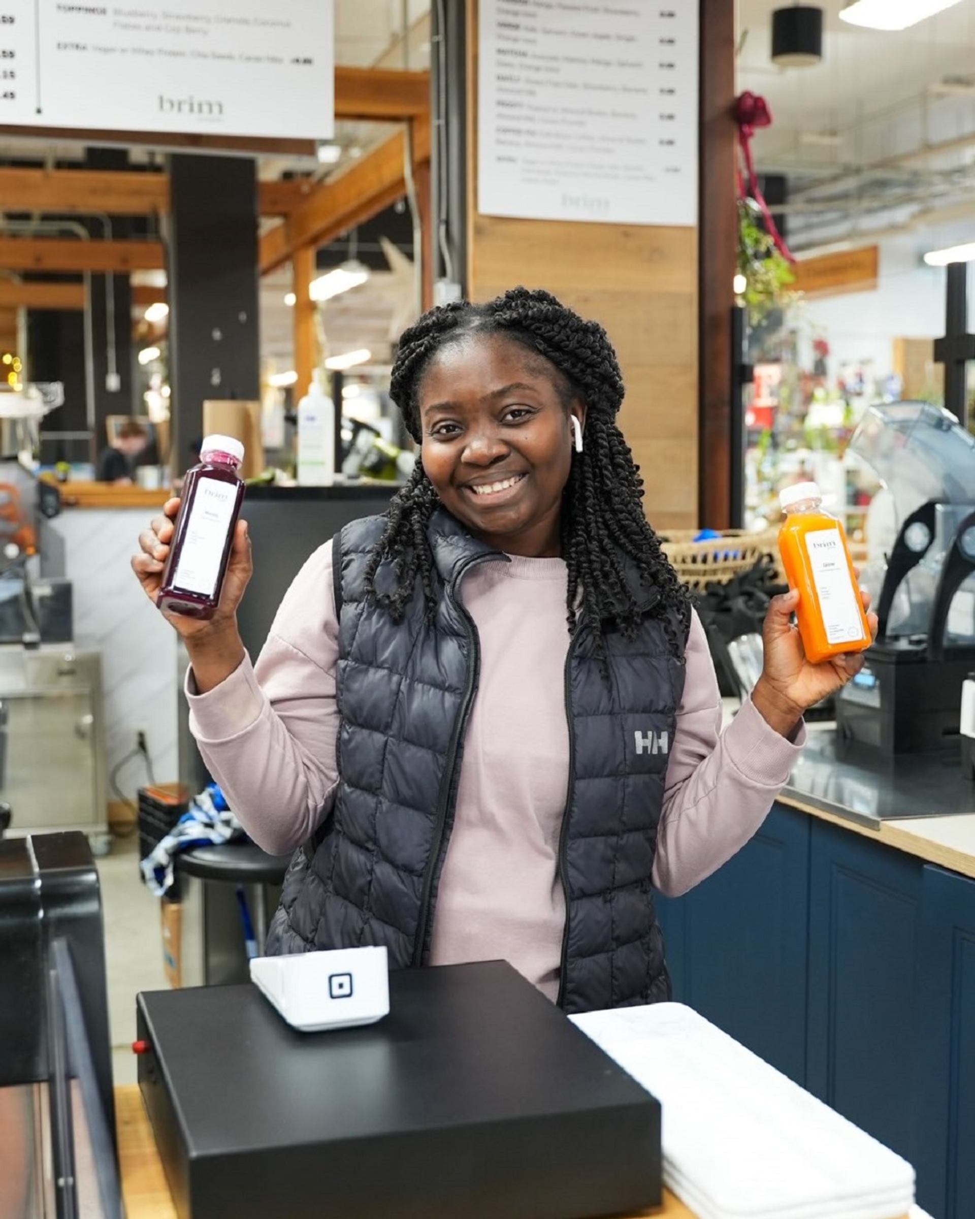 Person holding two bottled juices at a counter inside Crossroads Market.