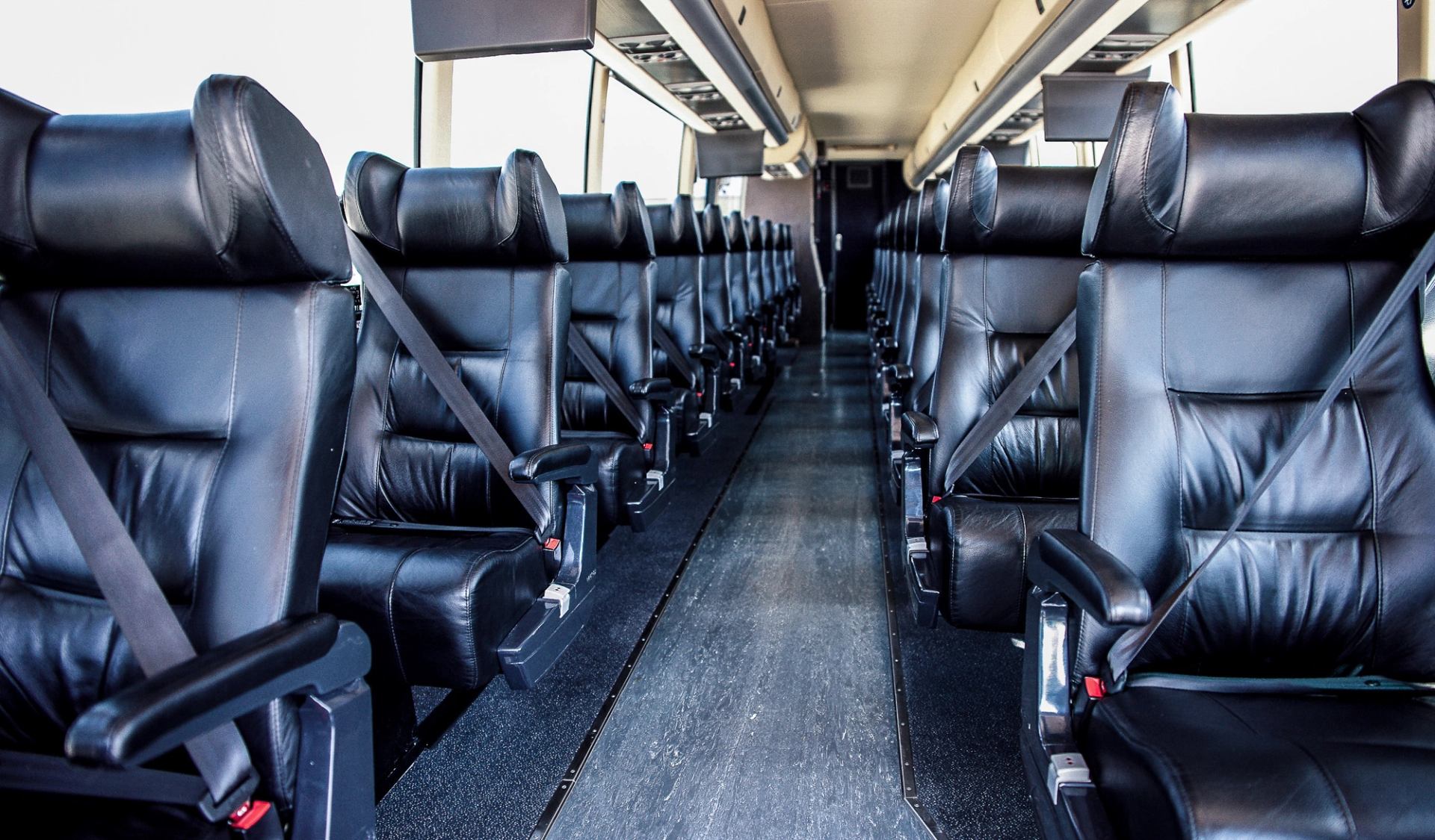 Bus interior with black leather seats and aisle on Red Arrow Motorcoach.