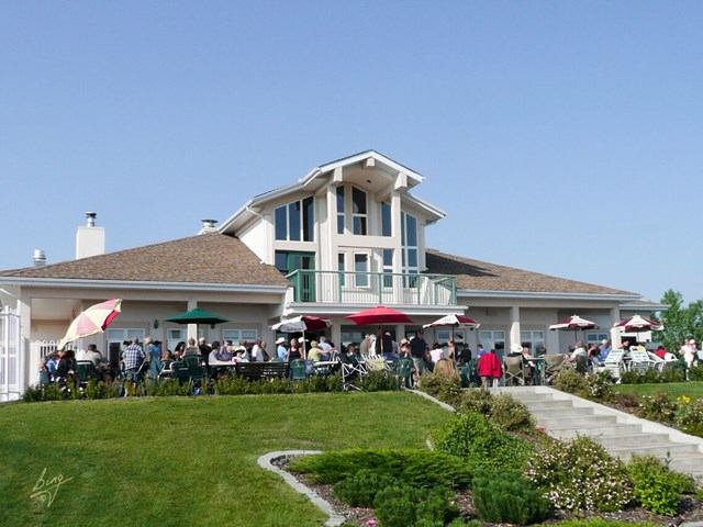 Resort building with patio, umbrellas, and guests amid landscaped greenery.