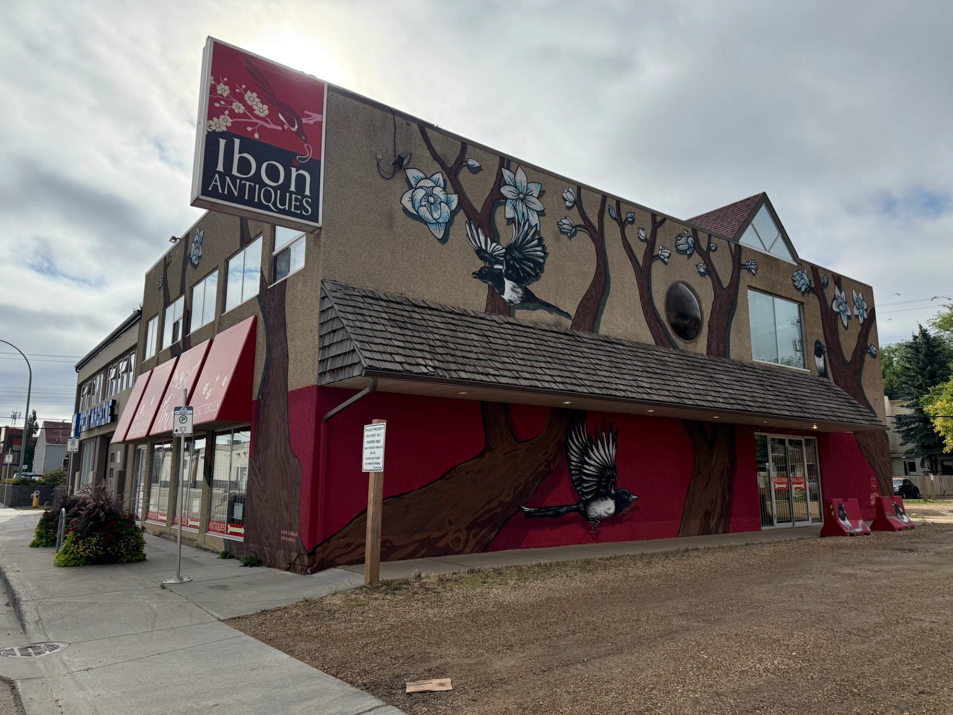 Street view of Ibon Antiques building with bird and tree mural on exterior walls.