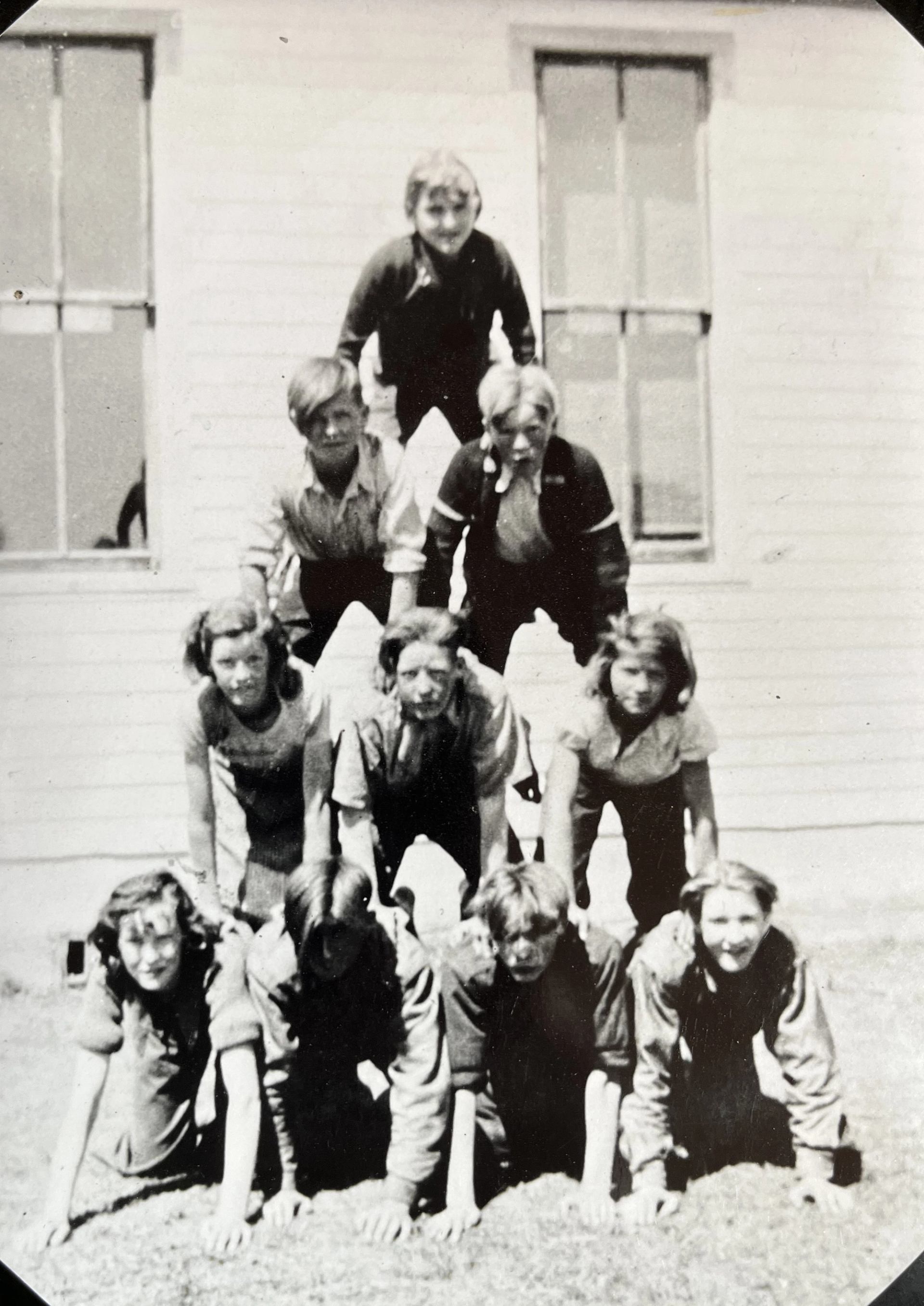 A group of children knelt on each other forming a pyramid.