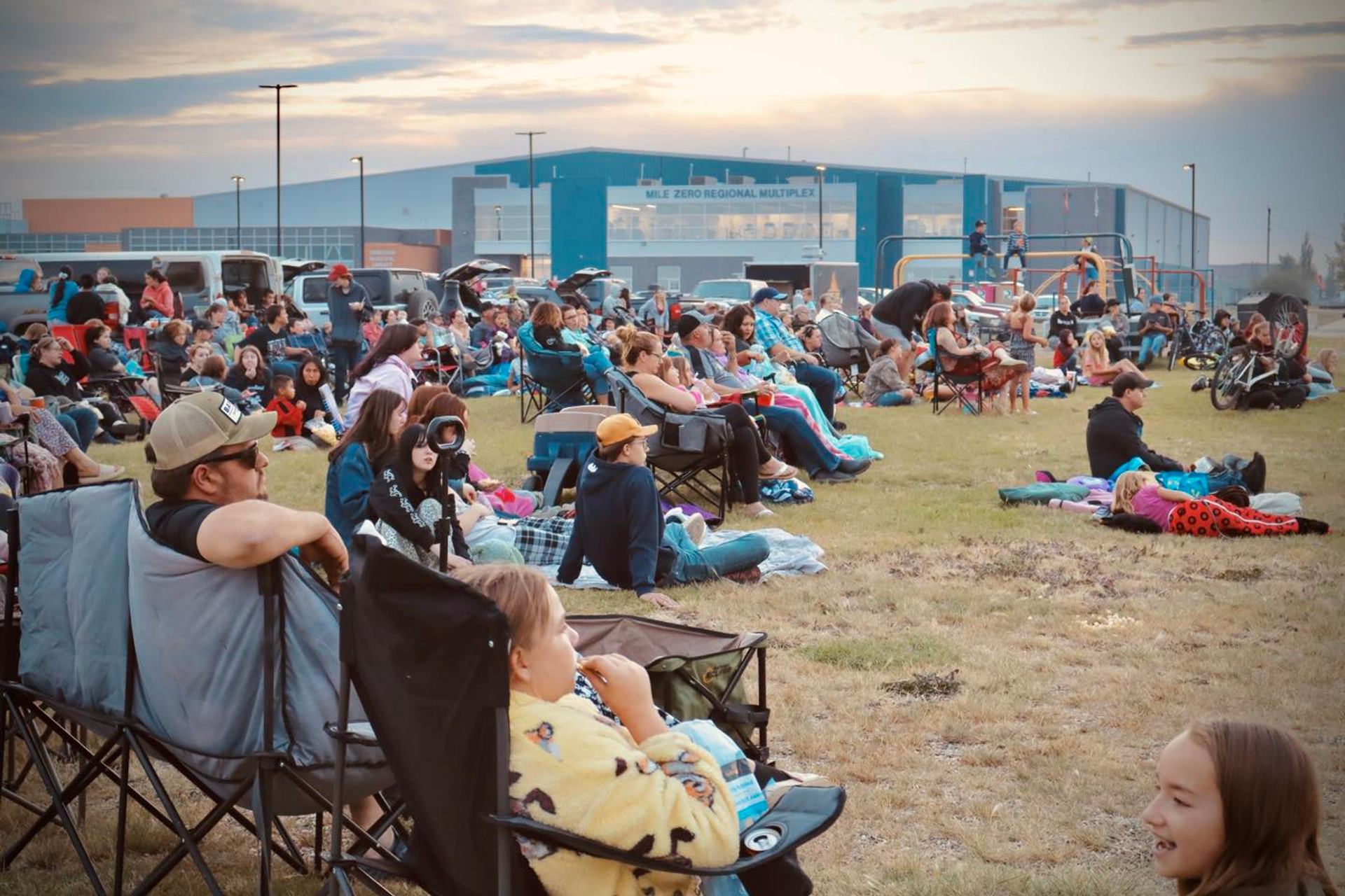 Crowd seated on blankets and lawn chairs watching outdoor entertainment at the Harvest Moon Festival.