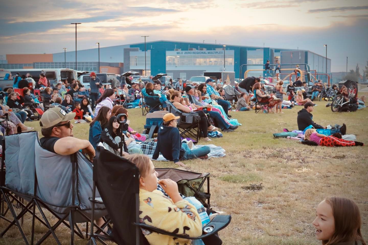 Crowd seated on blankets and lawn chairs watching outdoor entertainment at the Harvest Moon Festival.