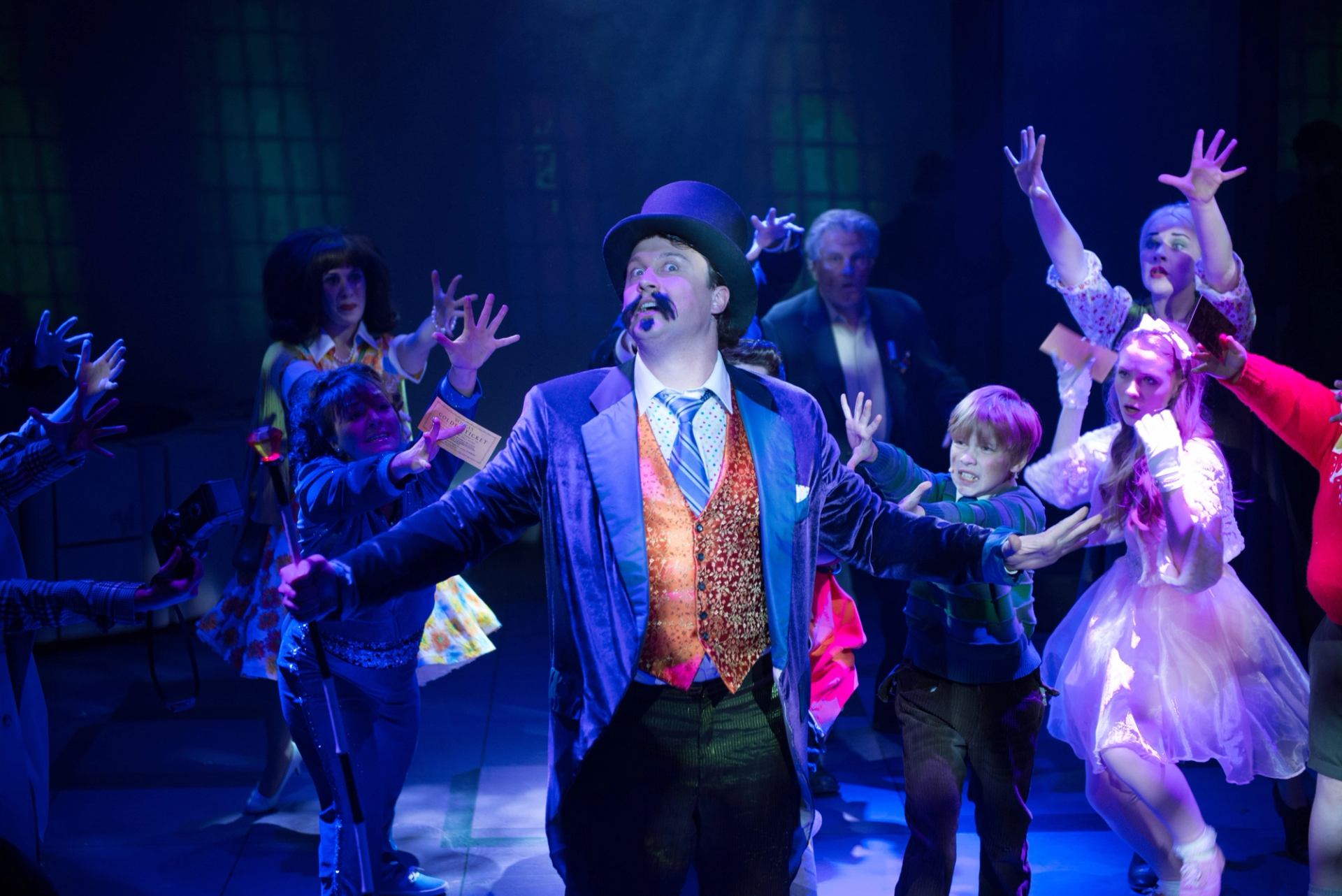 Performer in top hat leads cast on stage at Storybook Theatre.