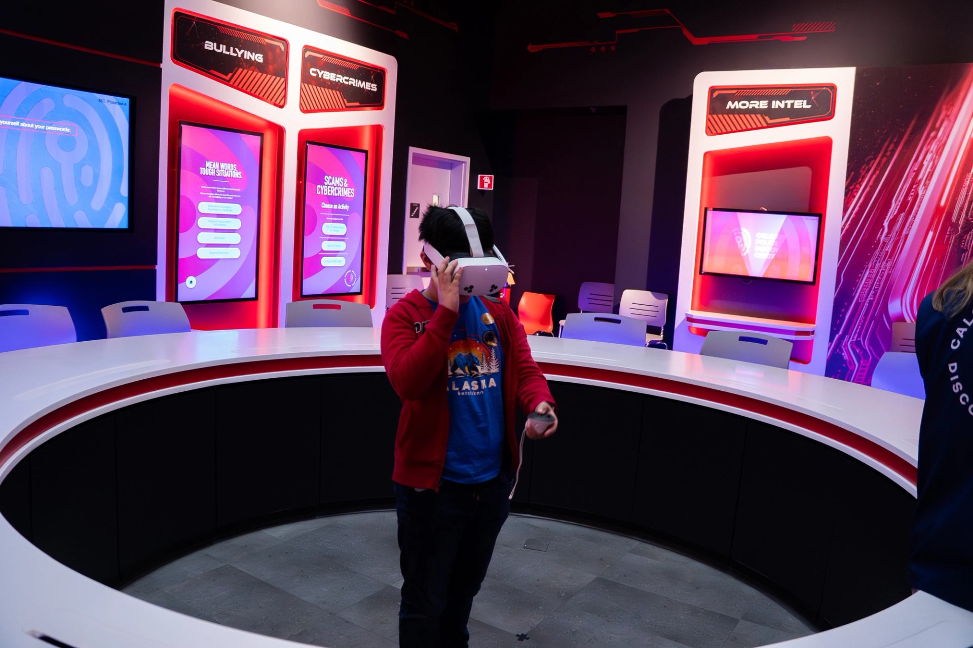 Person using a VR headset in a cyber safety exhibit with bright digital displays.