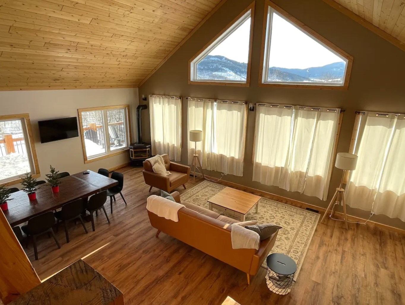 Cozy chalet-style living room with high ceilings, large windows, and mountain views.
