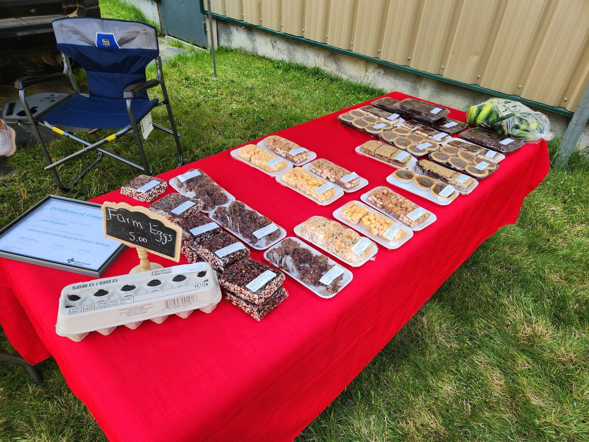 A market table features baking, farm eggs, cookies, tarts, squares, and locally produced treats.