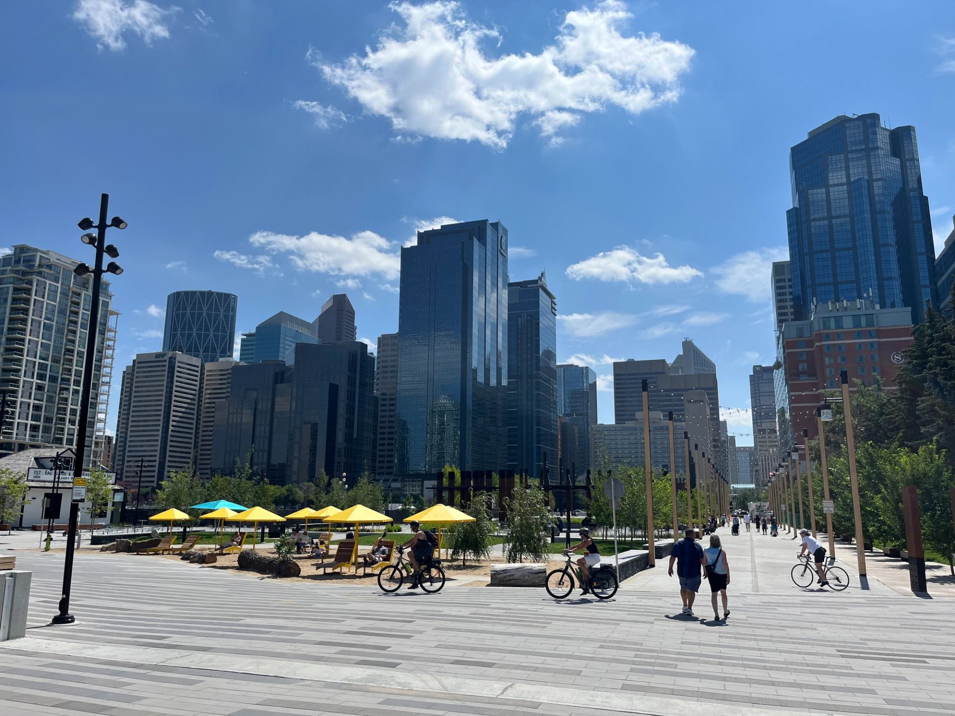 People walking and cycling through a modern downtown Calgary plaza.