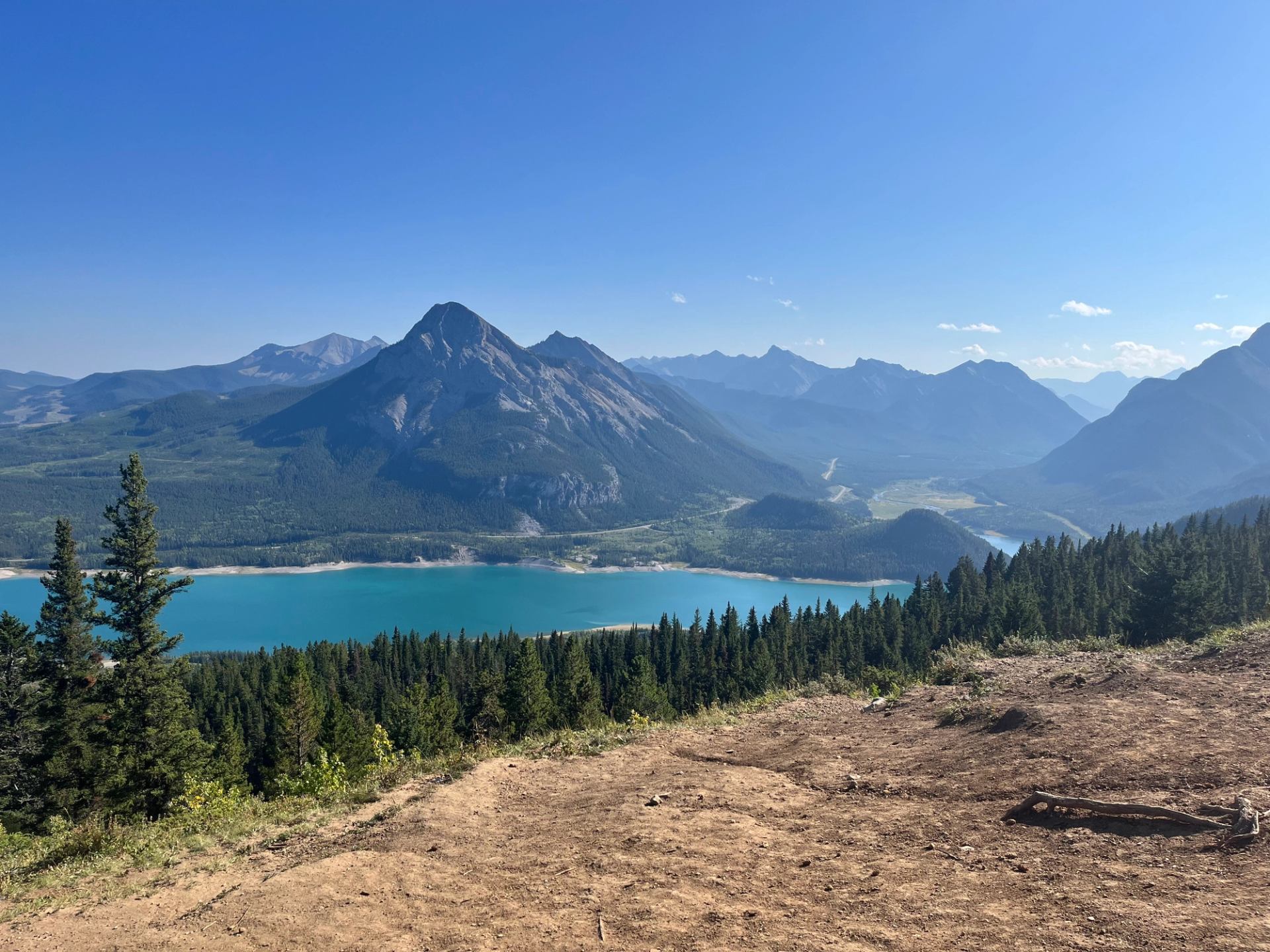 Scenic overlook showing a turquoise lake and tall mountain peaks.