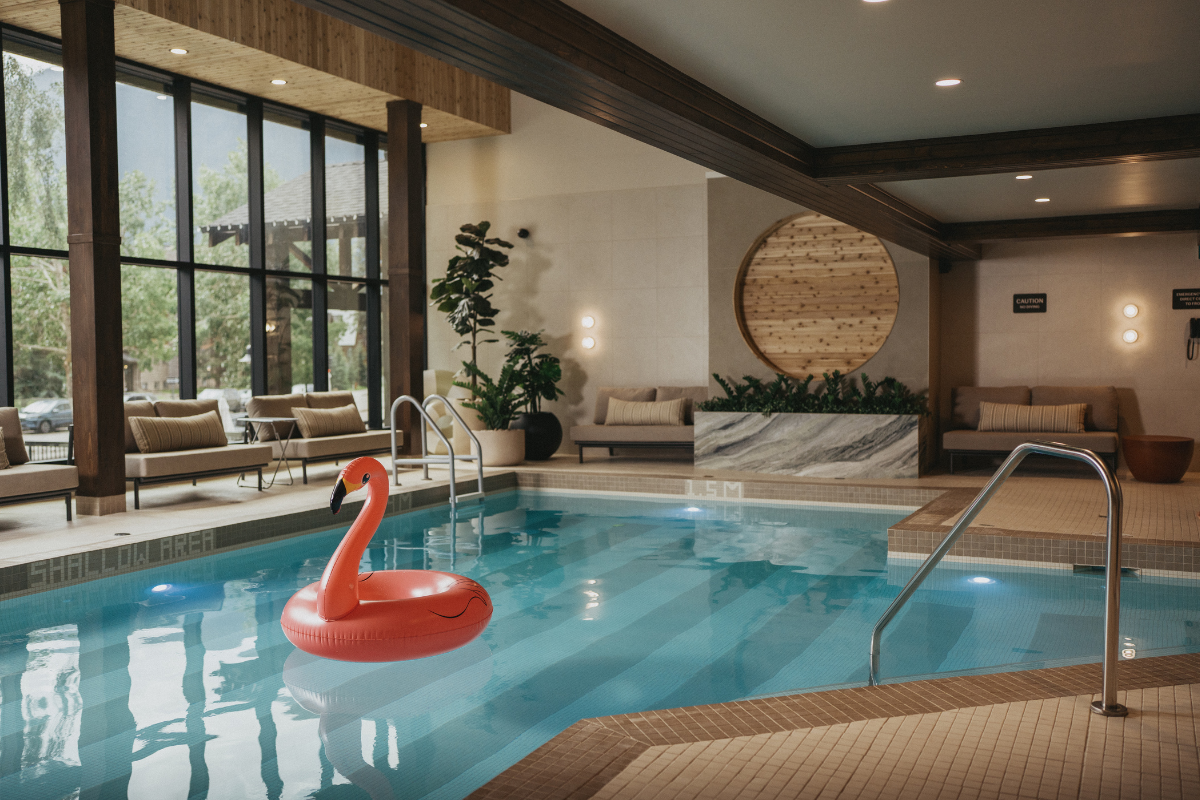 Indoor swimming pool with a pink flamingo float and large windows.