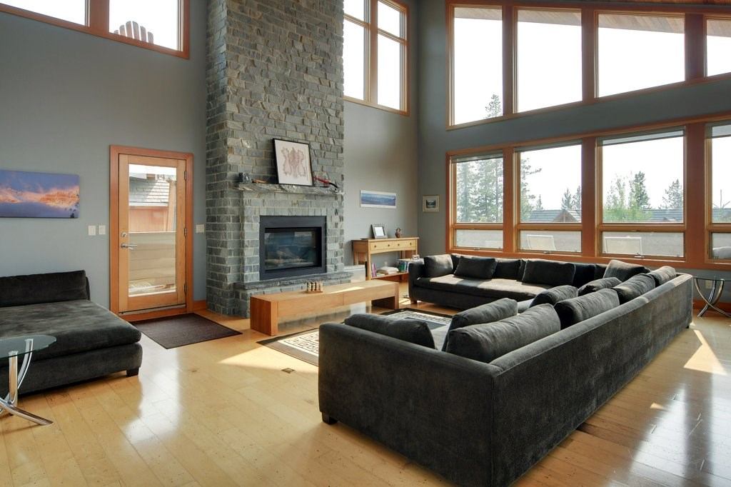 Spacious living room with stone fireplace, large windows, and sectional sofas.