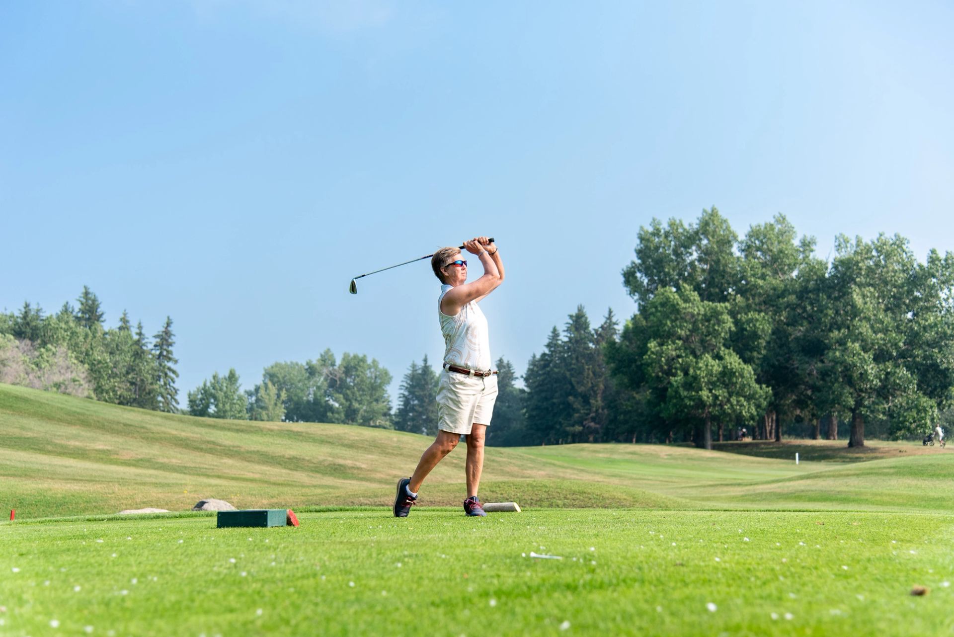 A golfer finishing a swing from the tee box of hole 4 of the Camrose Golf Course