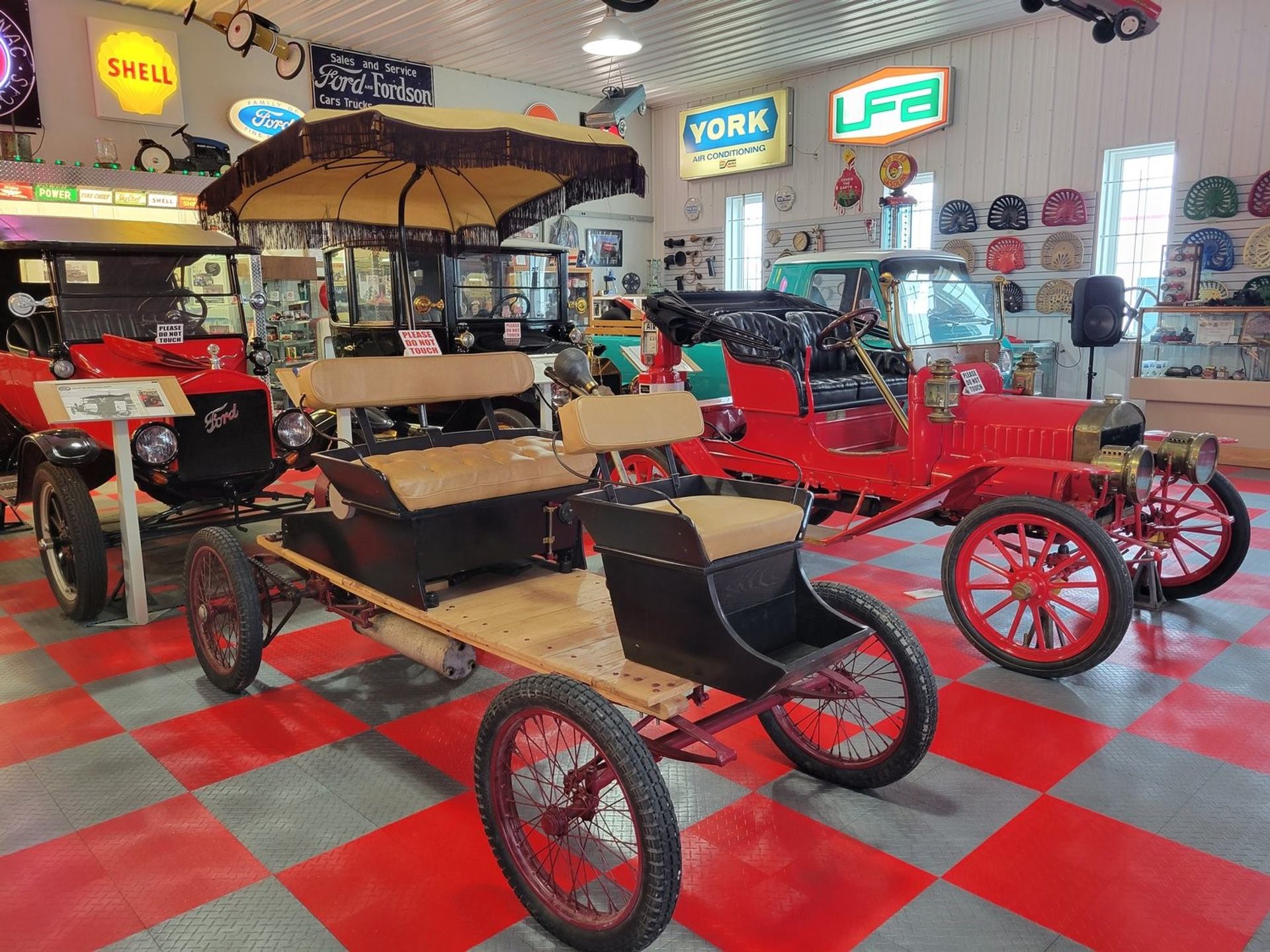 Red and black vintage horse-drawn carriage on display inside a museum showroom.