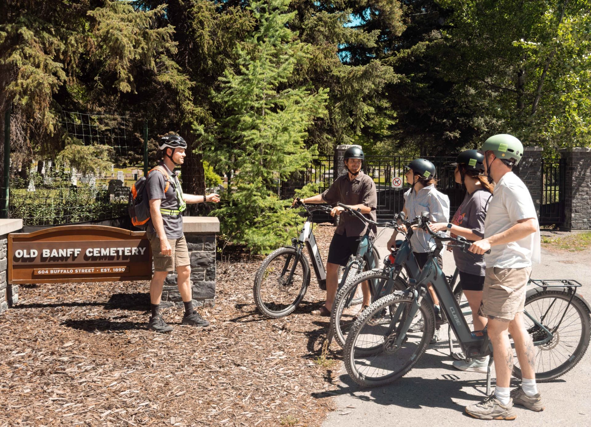 Group on e‑bikes stopped by the Old Banff Cemetery sign during a guided tour.