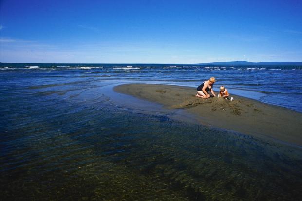 Grandmother and child paying in the sand on Devonshire Beach .