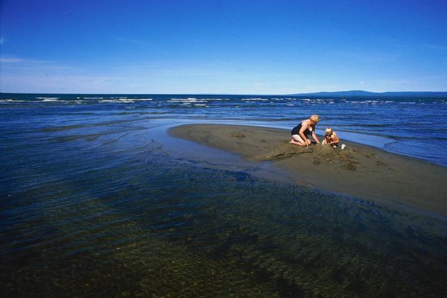 Grandmother and child paying in the sand on Devonshire Beach .