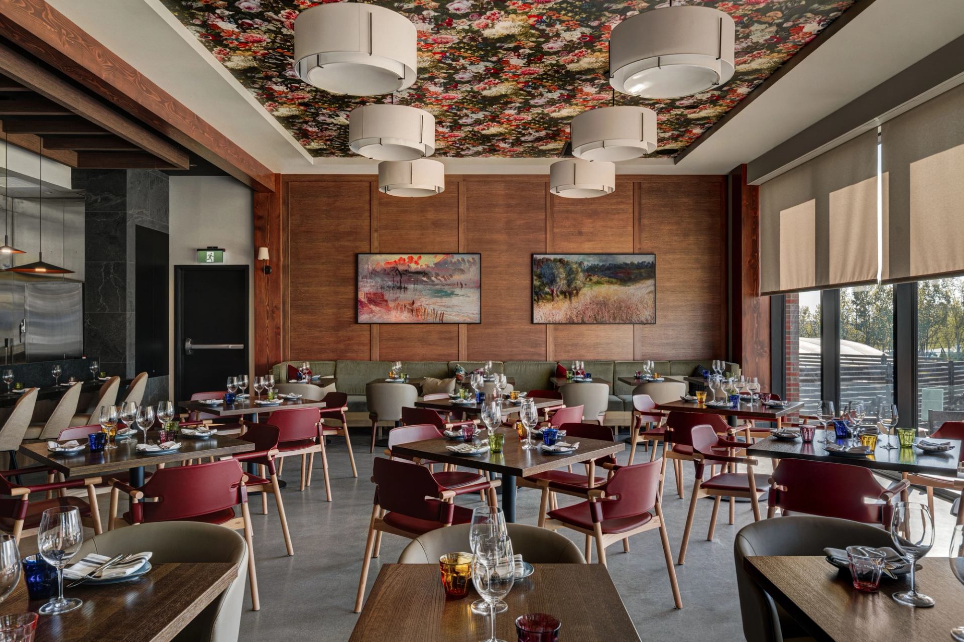 Dining room at Foxtrot at Spruce Meadows with set tables, wood walls, artwork, and floral ceiling.