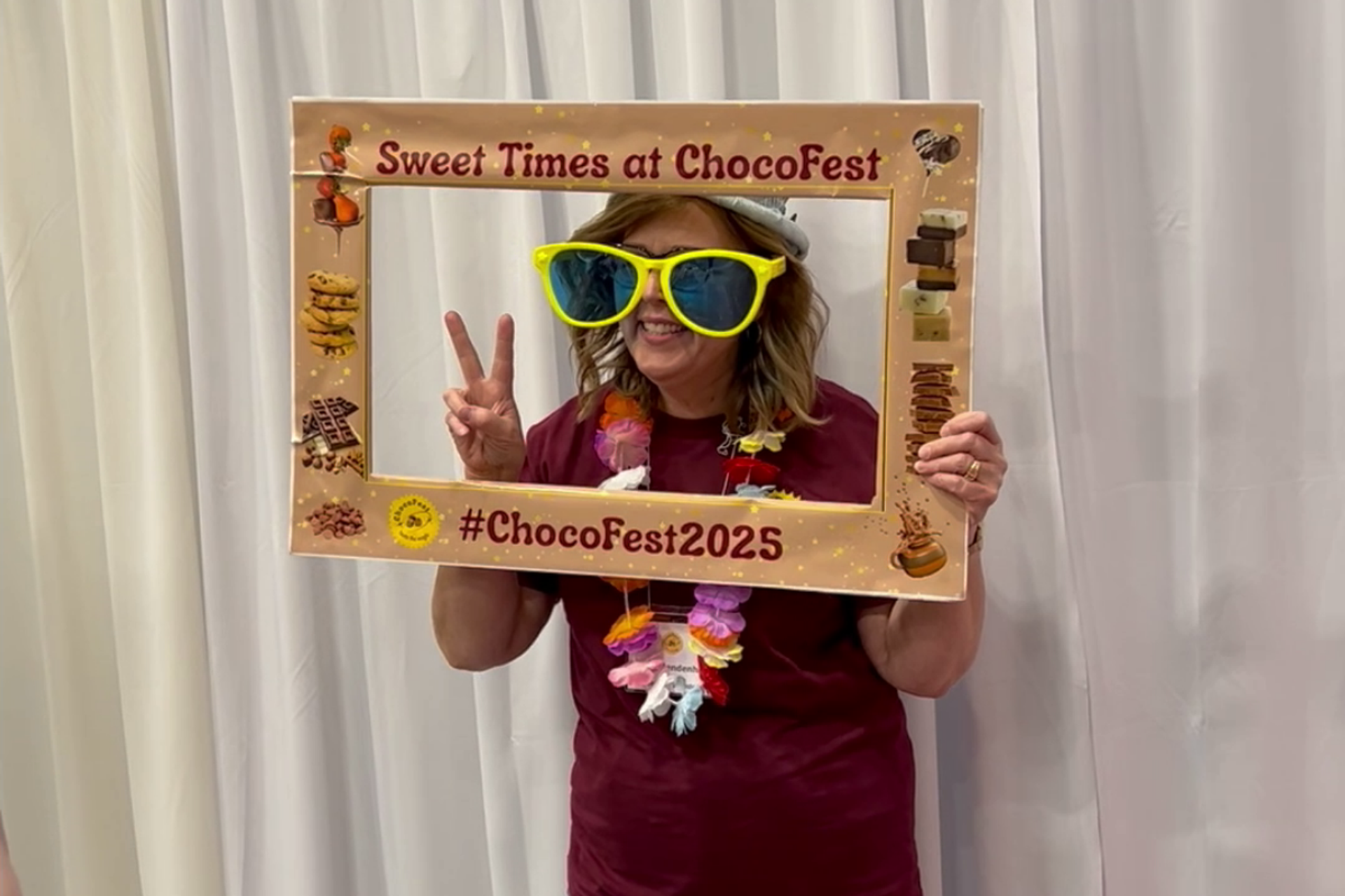 Person posing with a ChocoFest frame and oversized sunglasses.