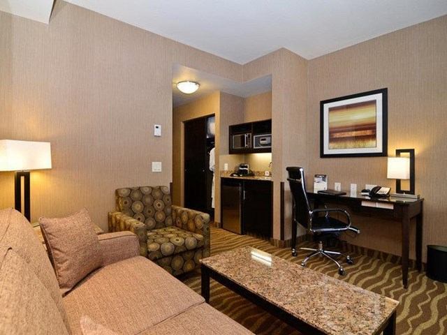 Comfortable hotel suite with sofa, desk, and kitchenette.