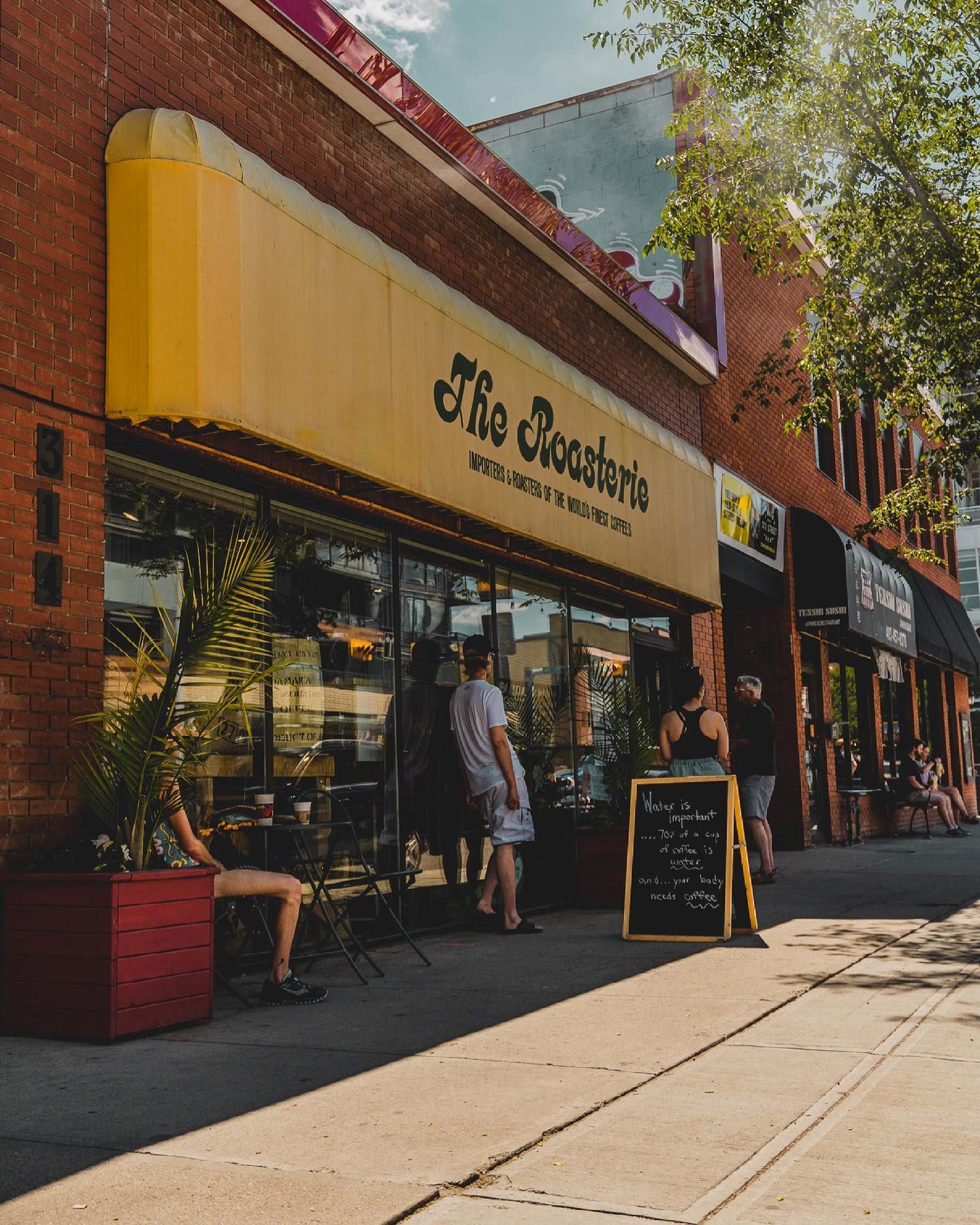 Exterior view of The Roasterie café with yellow awning and sidewalk seating.