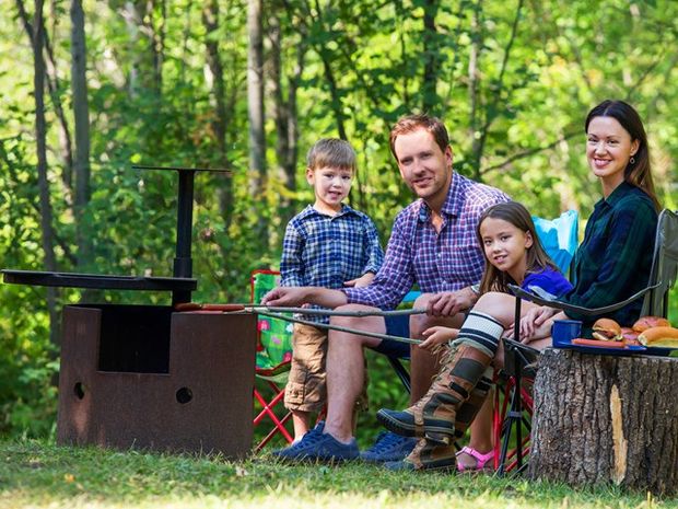 Family roating hot dogs at their campsite.