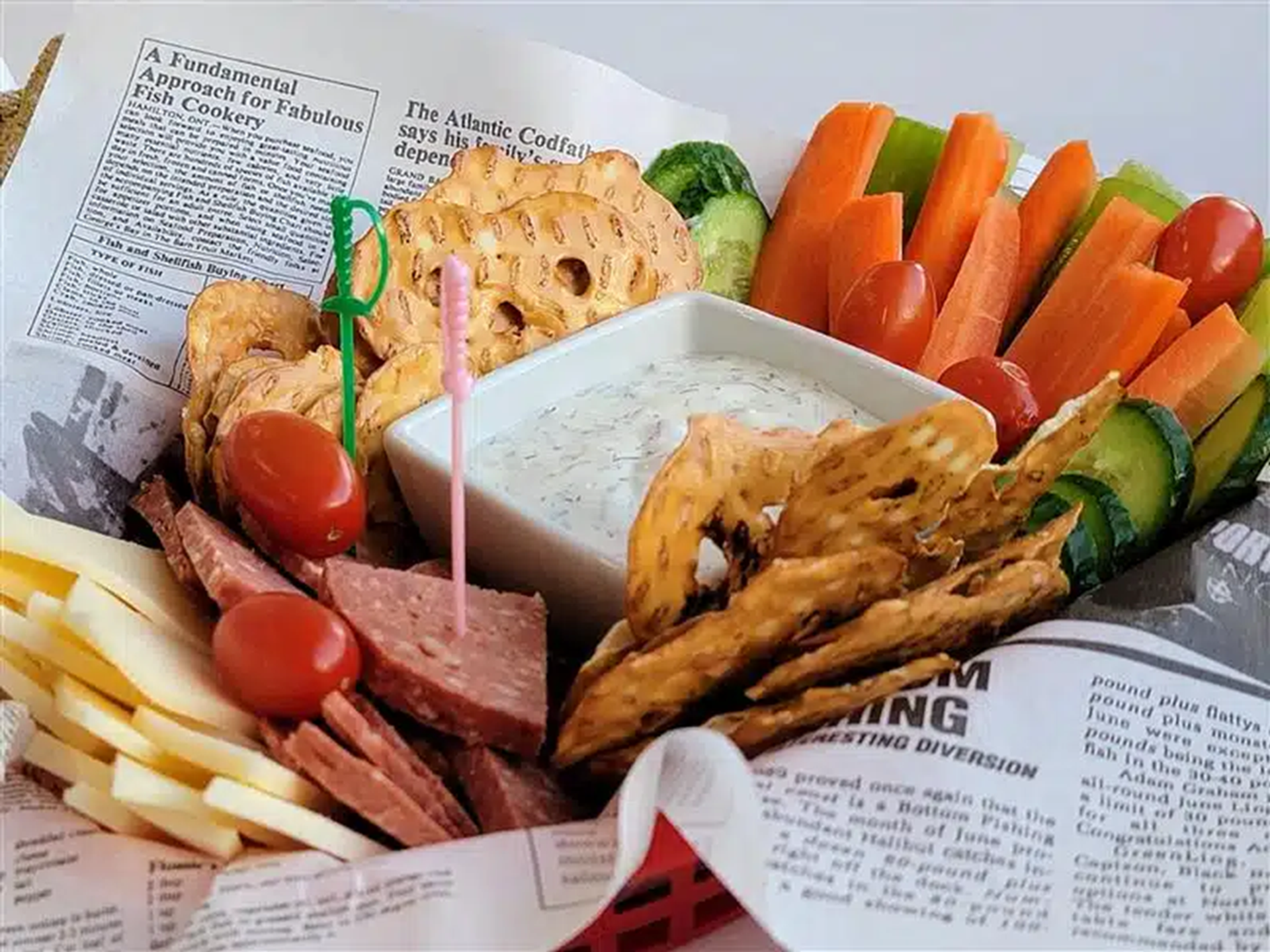 A tray of meat, cheese, crackers, veggies, and dip