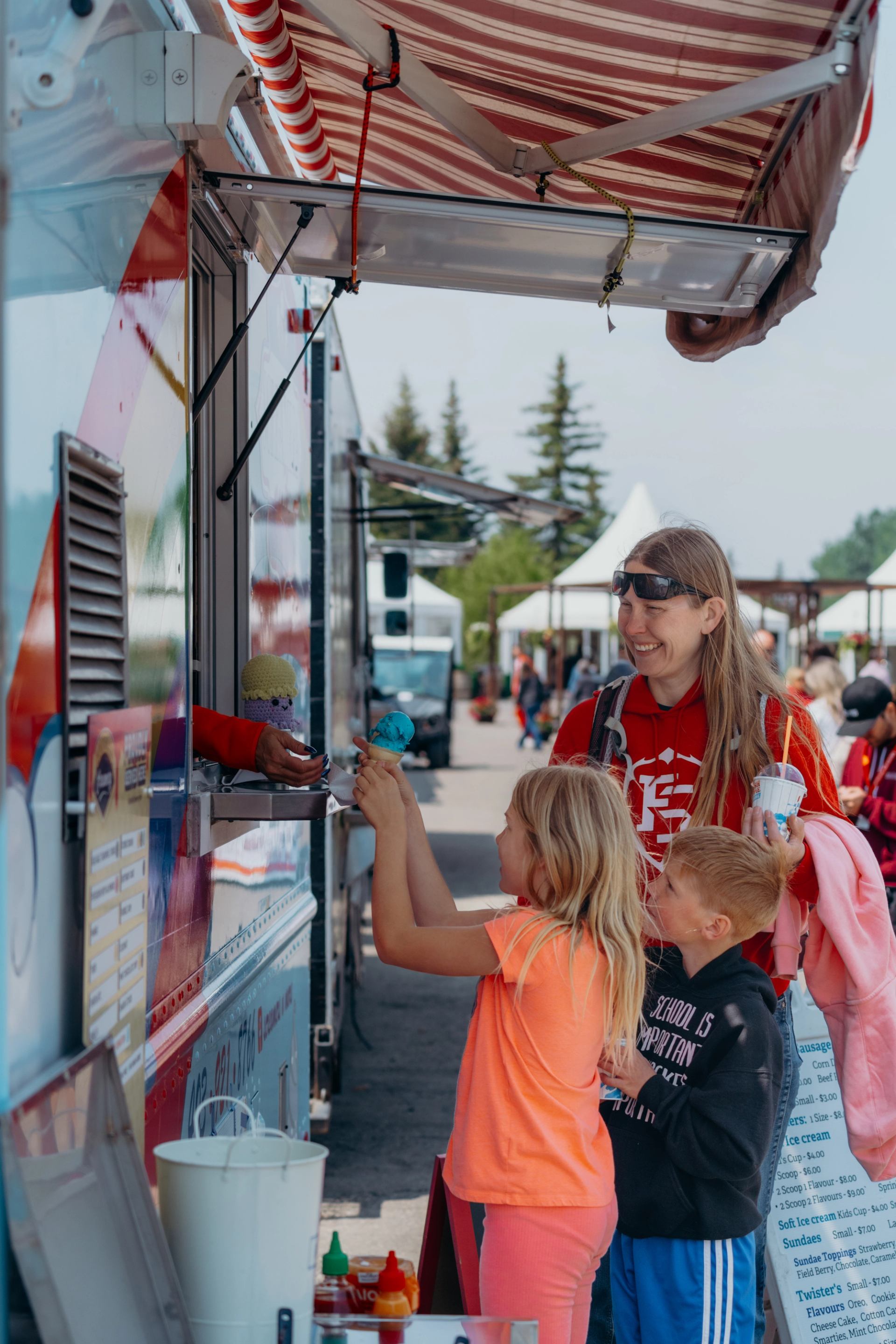 Children standing at a food truck counter receiving ice‑cream cones.