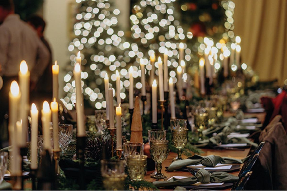 A long dinner table with place settings and several candles.
