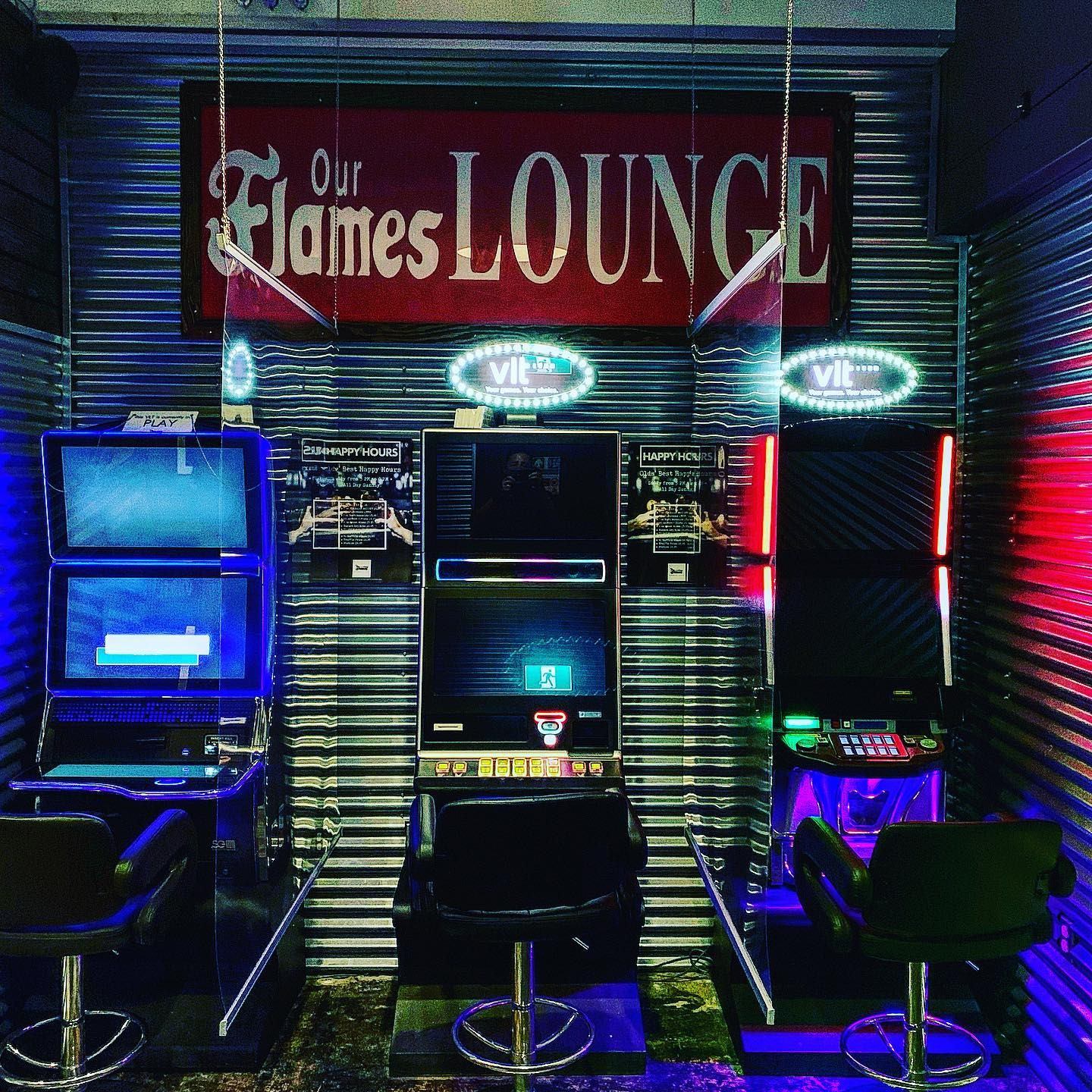Gaming machines lit up at Our Flames Lounge with vibrant lights and signage.