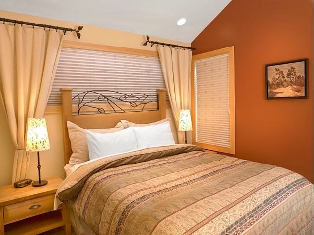 Warm-toned bedroom with striped bedding, wooden accents, and cozy lighting.