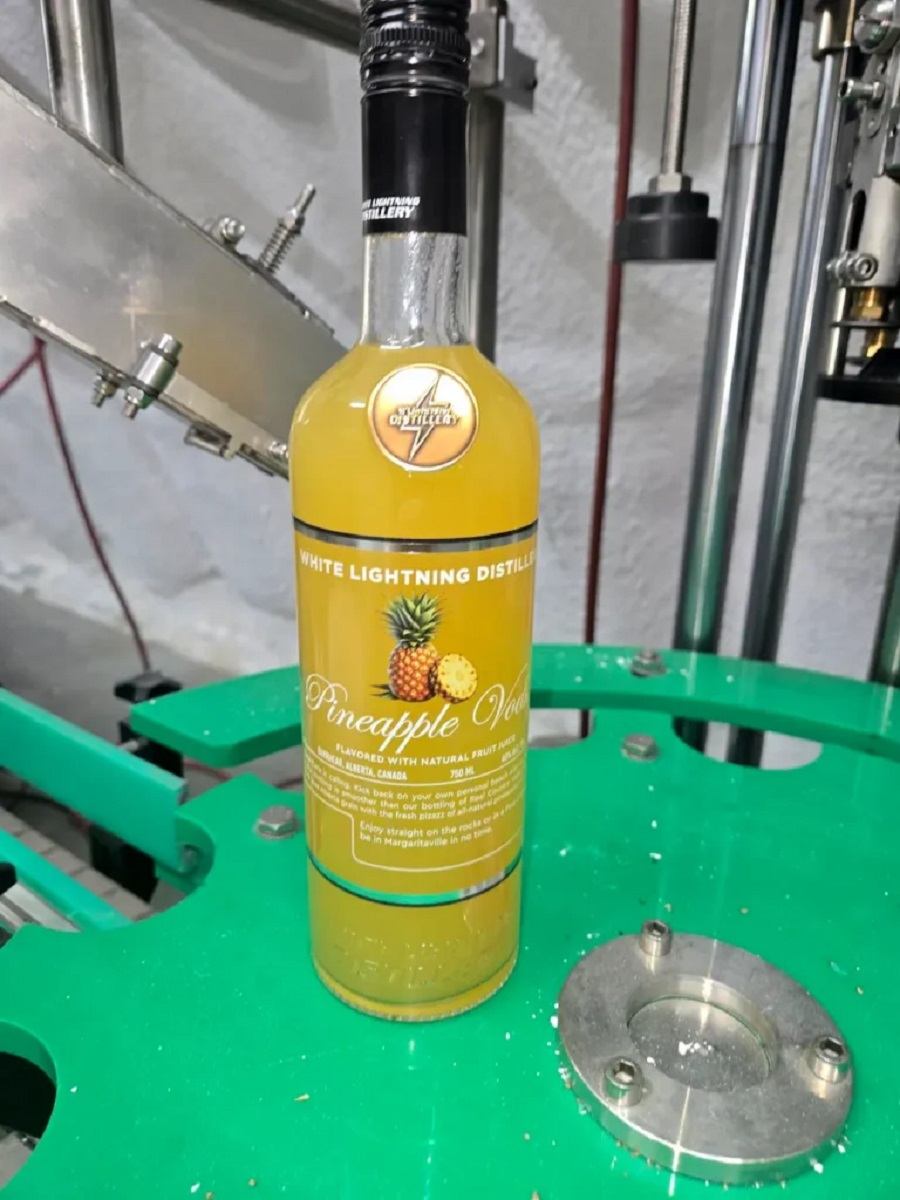 Pineapple vodka bottle from White Lightning Distillery on a bottling line inside the distillery.
