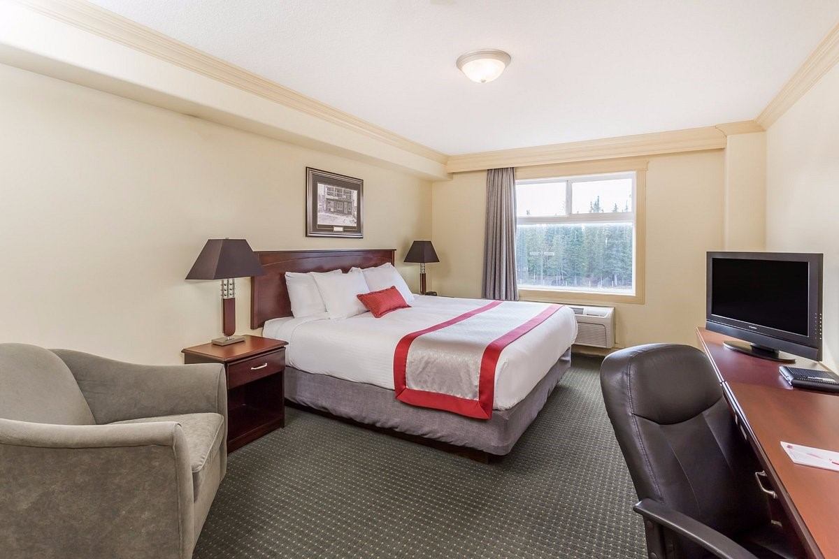 Cozy hotel room with red accents, desk, and natural light at Ramada Hinton.