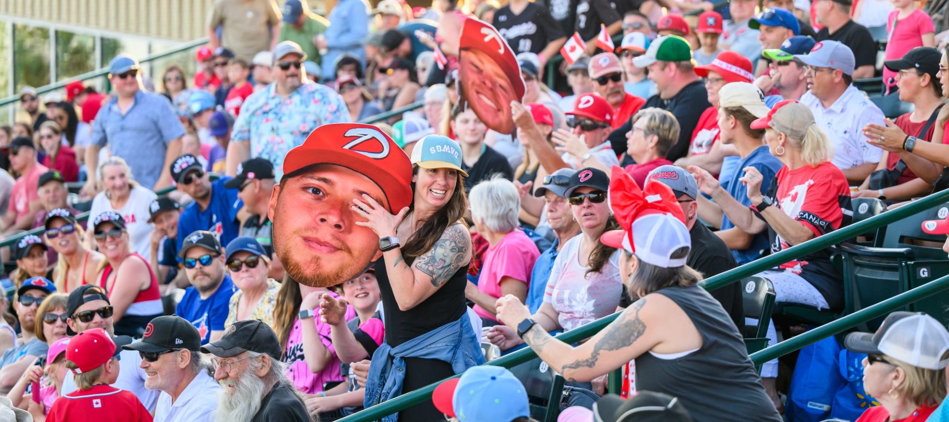 Crowd of baseball fans in stadium seats, many wearing red and cheering.