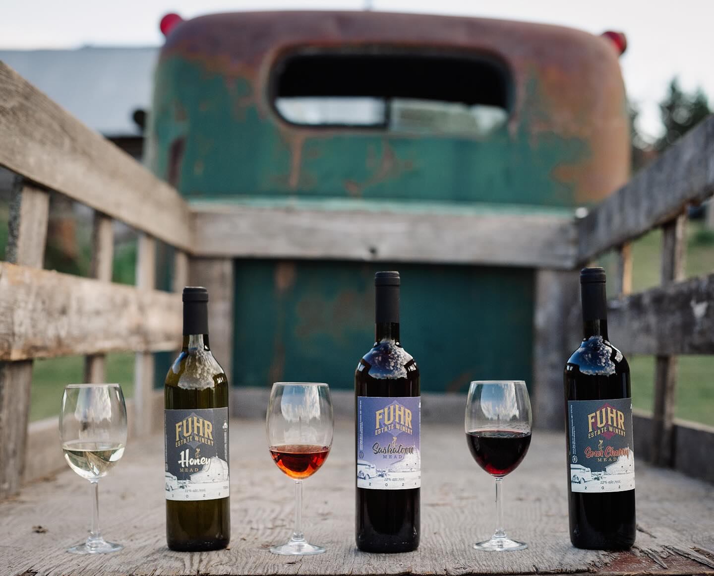 Three bottles of Mead in the back of an antique old pickup truck with a wooden box.